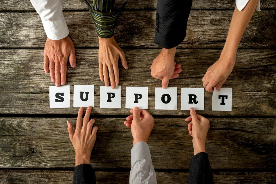 Seven hands holding each letter of “Support”